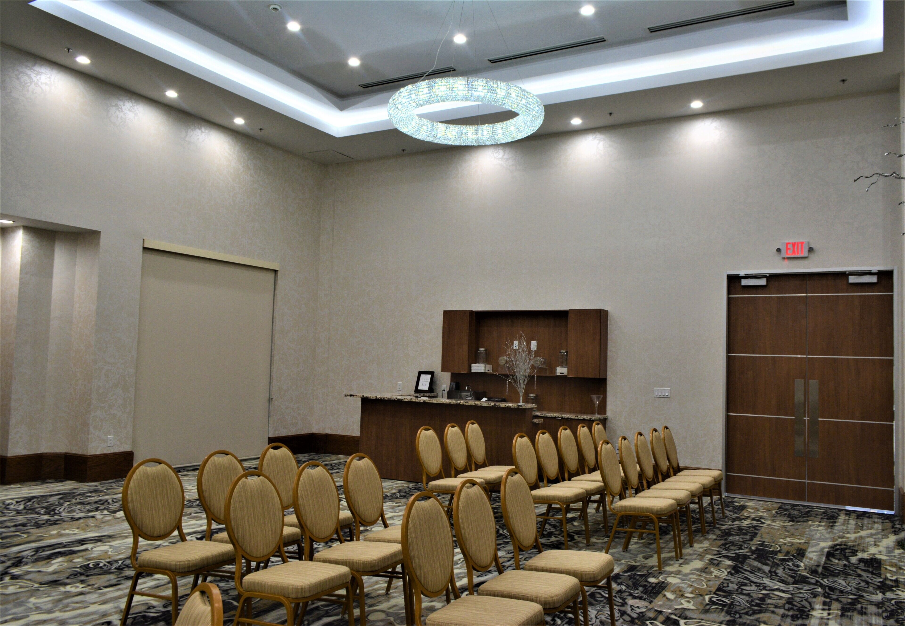 A conference room with rows of chairs, a reception desk, and a large wooden door.