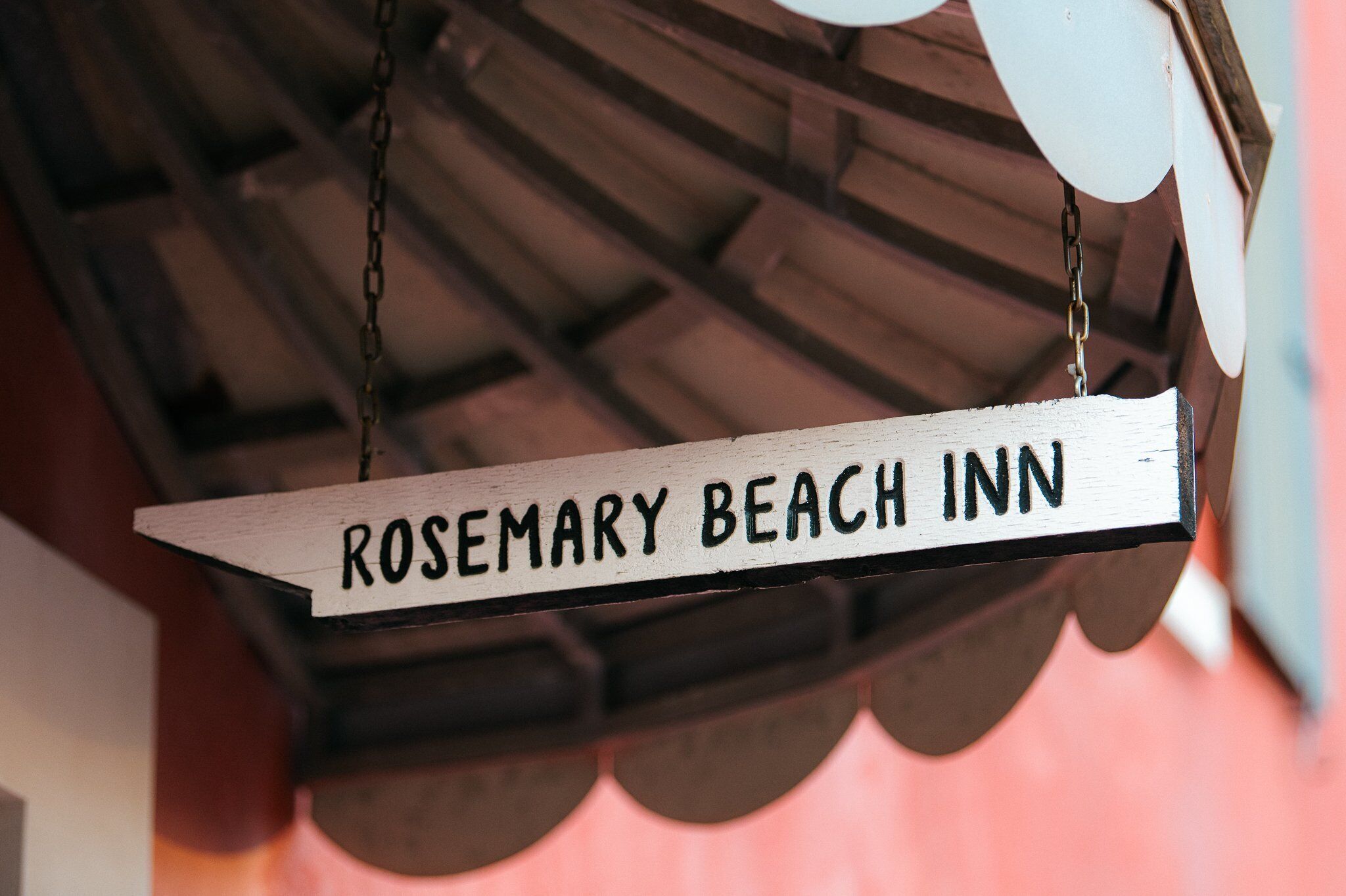 Une enseigne en bois portant l’inscription « ROSEMARY BEACH INN » et suspendue à une chaîne.
