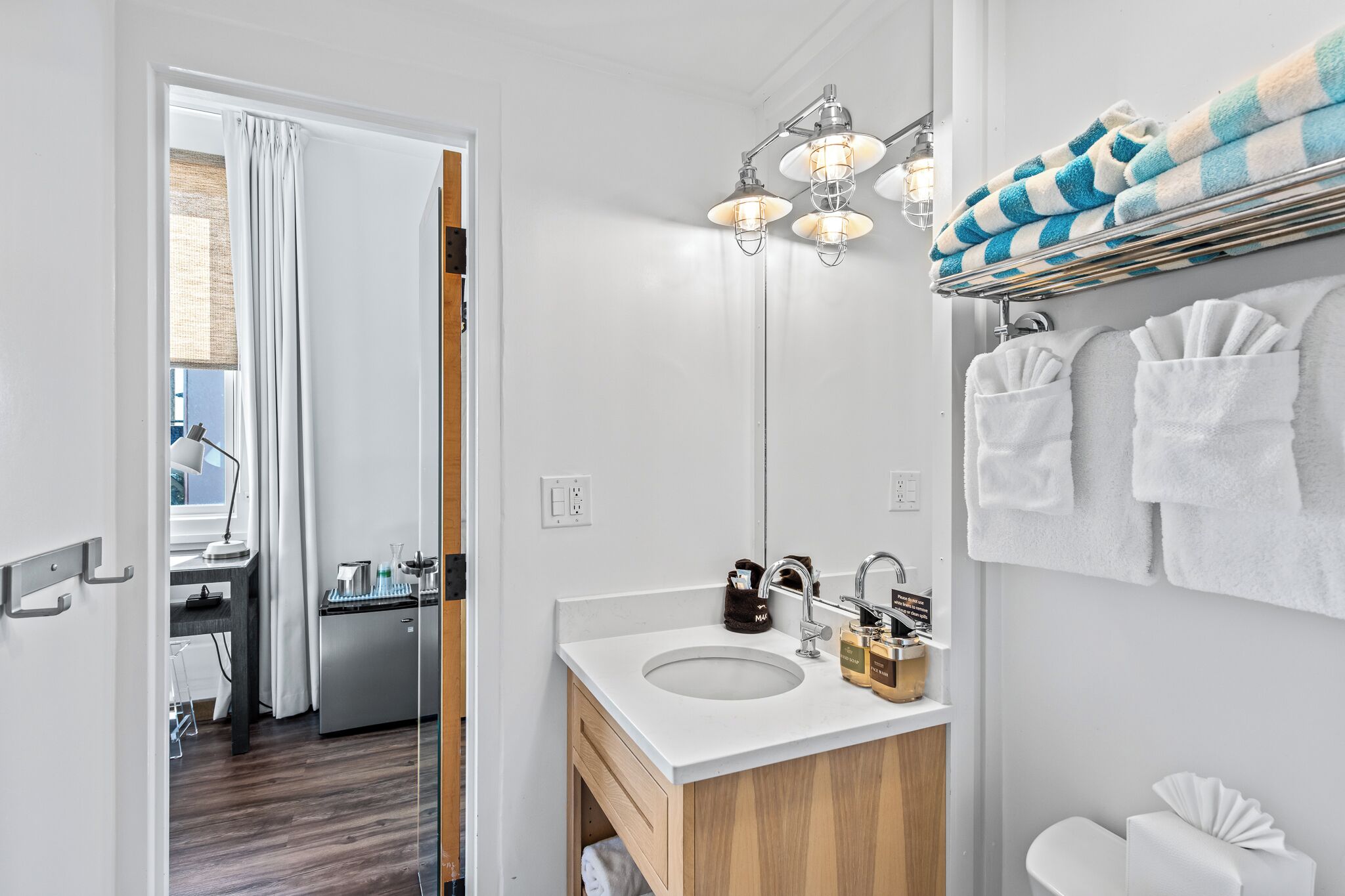 A modern bathroom with a double sink, wooden vanity, and a towel rack with striped towels.