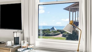 Une chambre d’hôtel moderne dotée d’une grande fenêtre donnant sur la mer et agrémentée d’un belvédère.