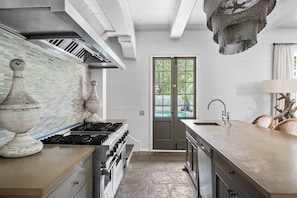 A modern kitchen with a large island, a gas stove, and a built-in oven.