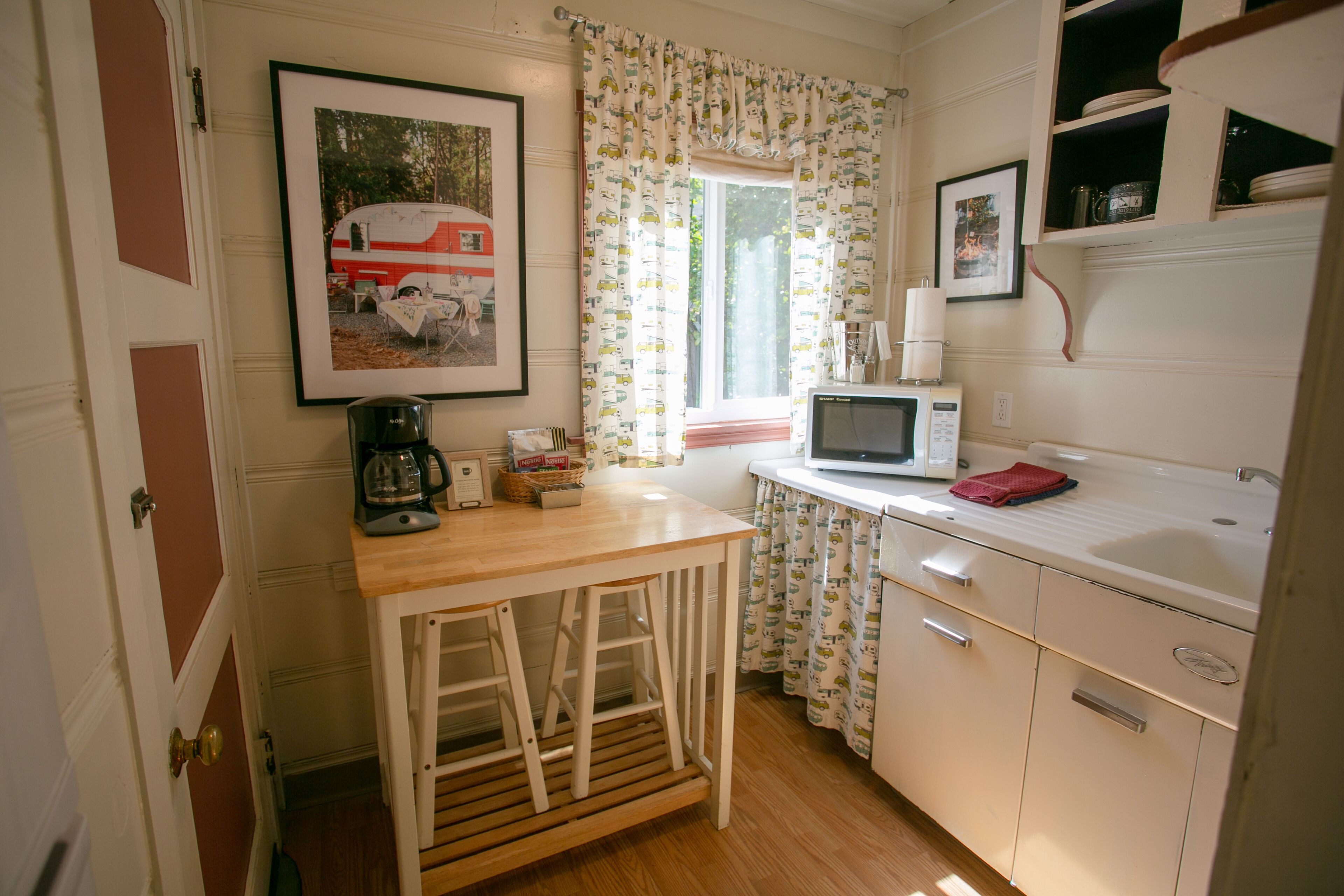 Una cocina funcional con una mesa de madera, un microondas y un lavabo.