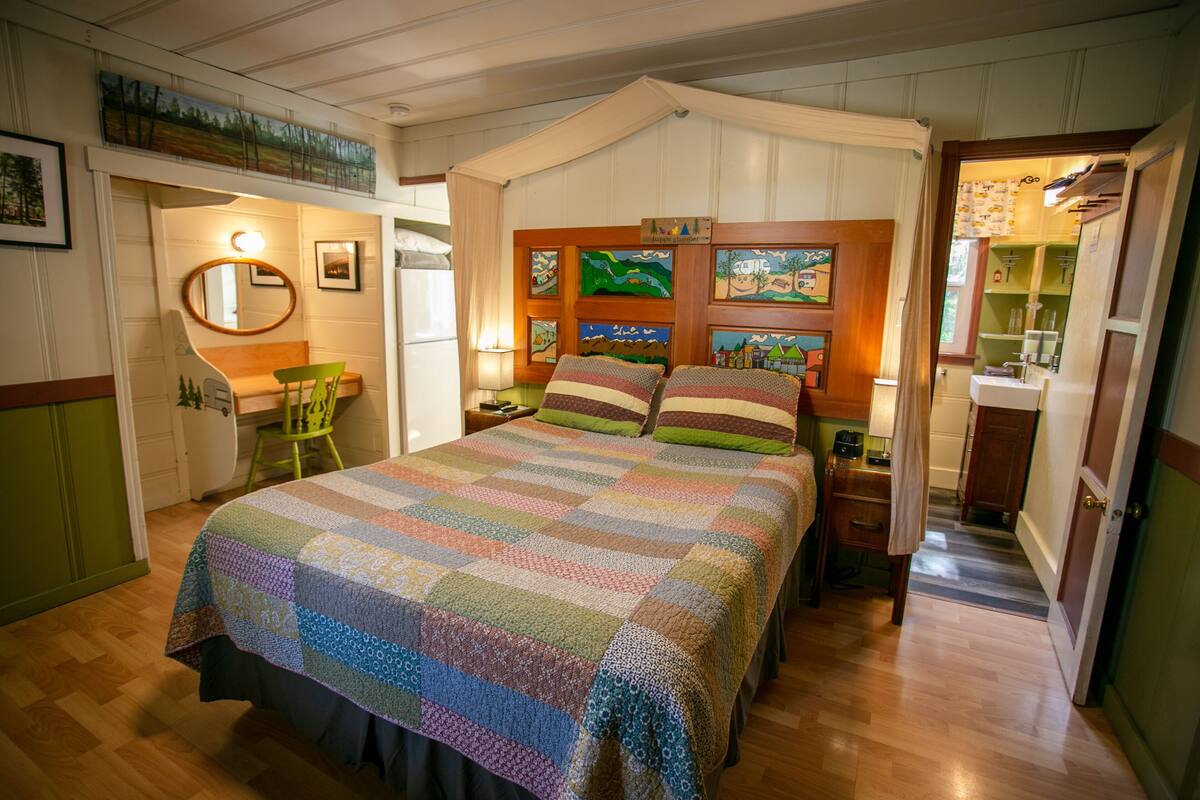 A cozy bedroom with a large bed, a wooden headboard, and a wall decorated with children's artwork.