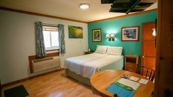 A bedroom with a bed, a wooden table with a chair, a window with curtains, and wall-mounted lamps.