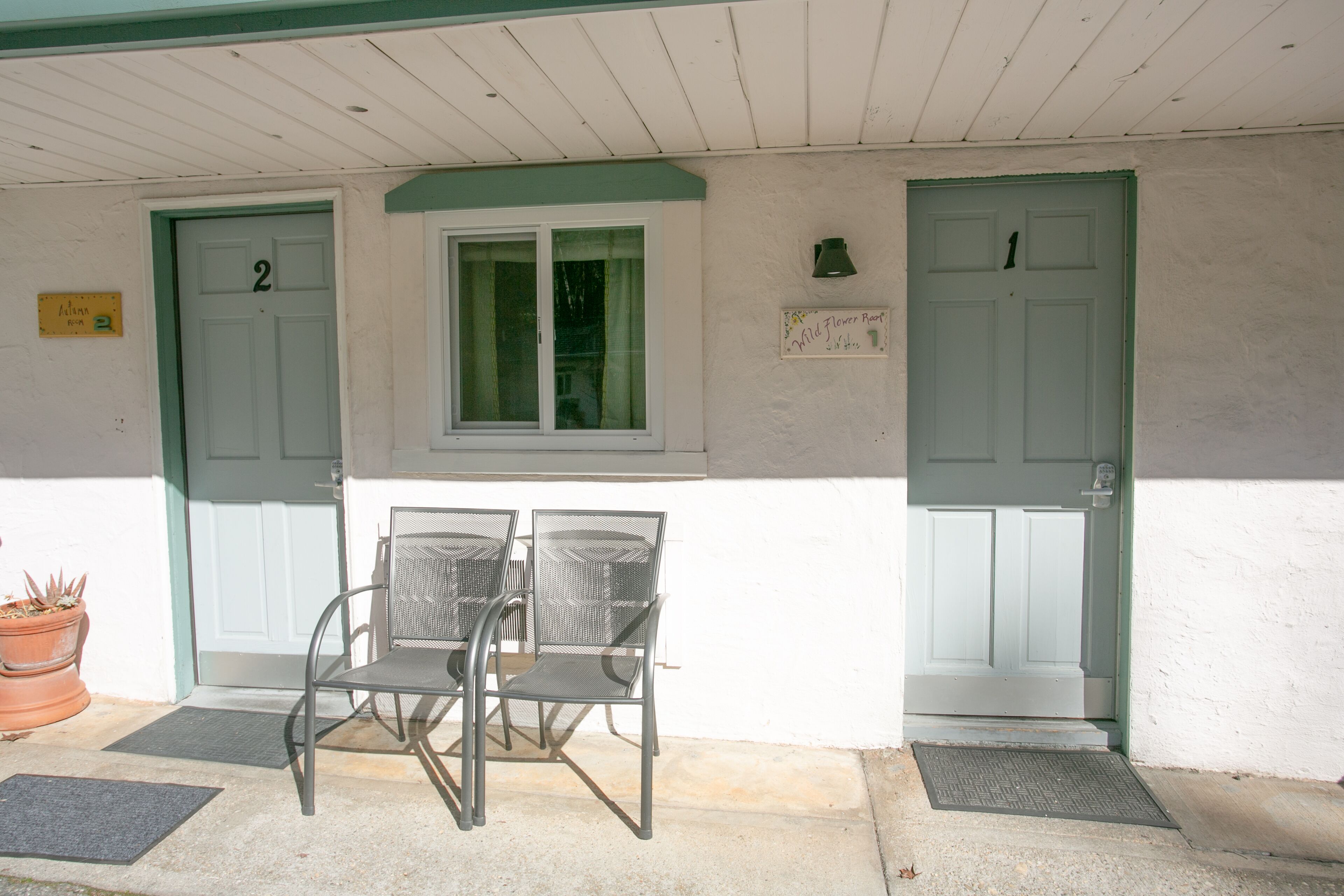 A building entrance with two doors, a window, and a table with chairs.
