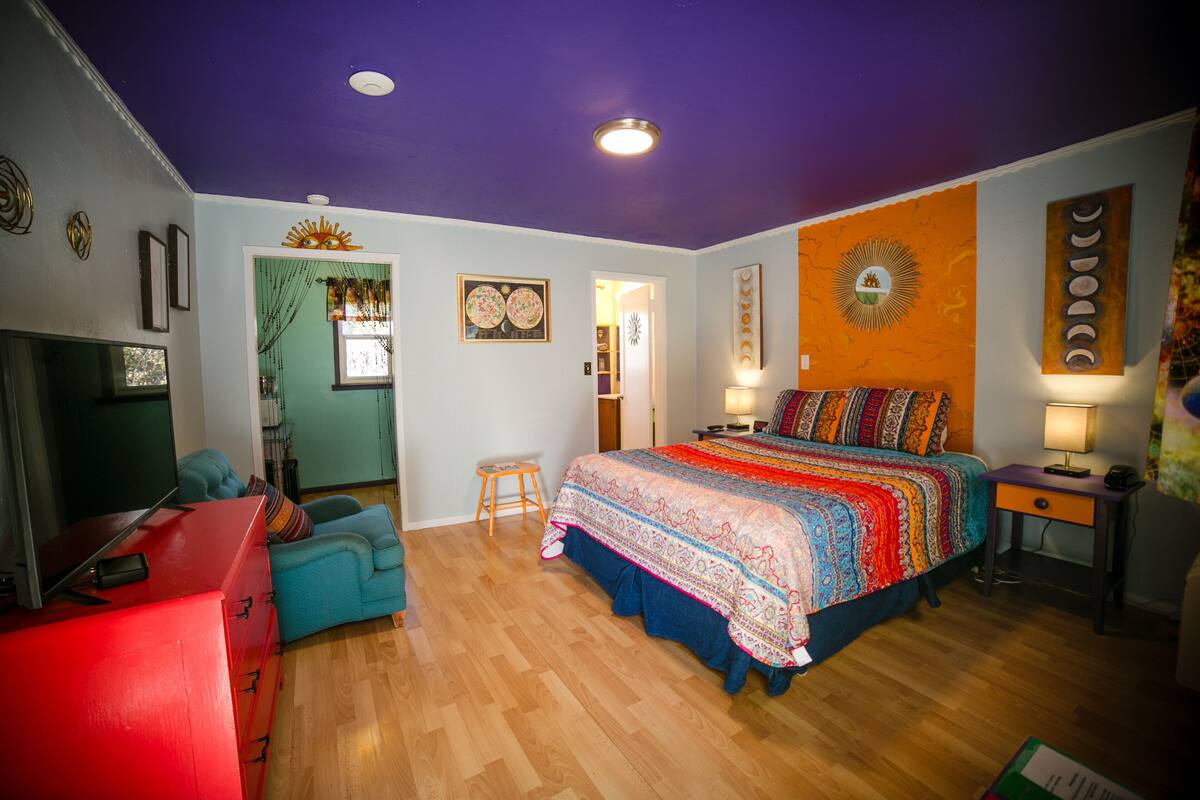 A bedroom with a bed, a TV, a desk, and a chair.