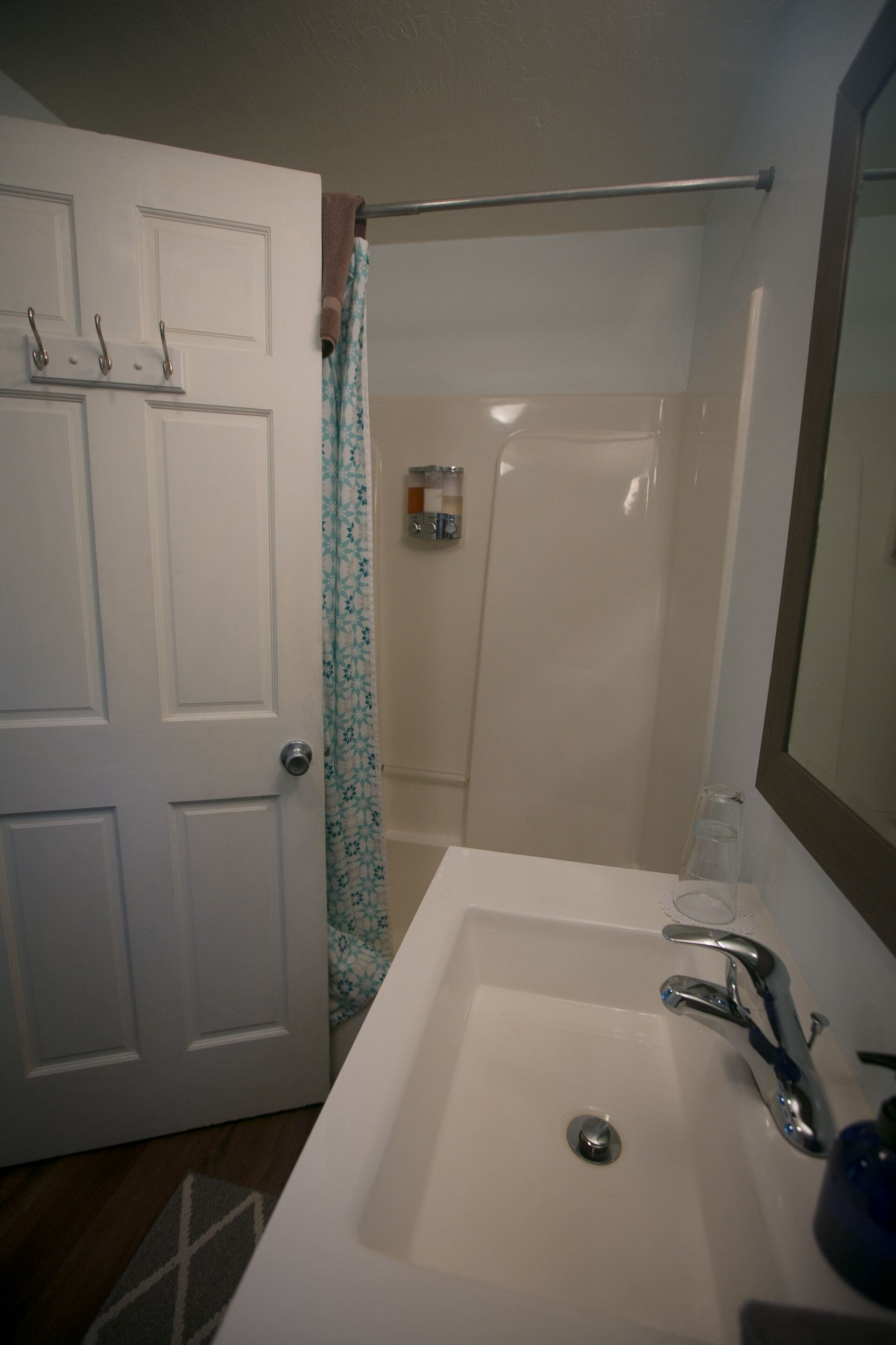 A bathroom with a white sink, a mirror, a towel rack, and a shower curtain.