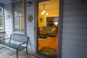 A wooden bench outside a house with a welcome mat at the entrance.