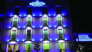 A hotel facade with illuminated signage reading "ROYAL MADERO INN" and "HOTEL ESTACIONAMIENTO".