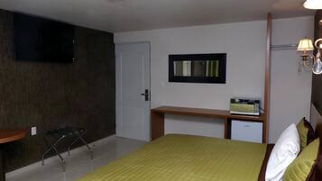 Une chambre d’hôtel équipée d’un lit, d’un bureau, d’une télévision, d’un four à micro-ondes et d’un petit réfrigérateur.