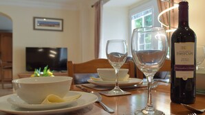A dining table set with a bowl of food, two wine glasses, a bottle of wine, and cutlery. - Victoria House - UK13380 (Llansteffan, near Carmarthen)