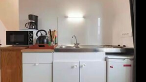 Eine kleine Küche mit Mikrowelle, Wasserkocher, Spüle und Schränken.