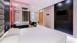 A modern hotel room with a large bed, a desk, and a TV mounted on the wall. - Plaza Motel - Adults Only (Votorantim)