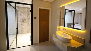A modern bathroom with a large mirror, a white sink, and a door leading to a shower area. - Plaza Motel - Adults Only (Votorantim)