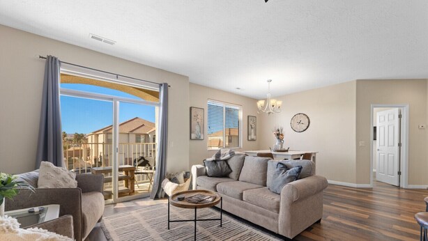 A spacious living room with a large sliding glass door leading to a patio, a cozy seating area with a sofa and armchairs, and a dining area with a table and chairs. - Newly Renovated Sparkling Springs by J and Amy BL990802 (Mesquite)