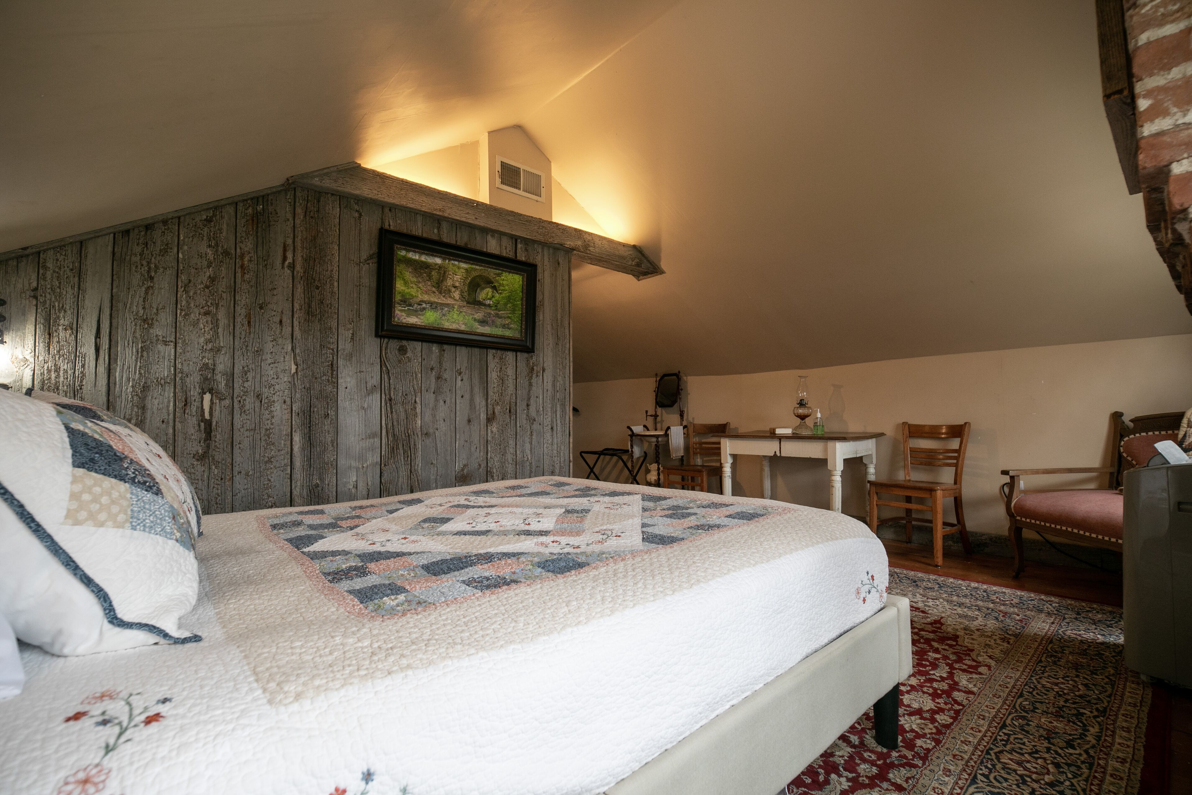 Un dormitorio con cabecera de madera, colcha, escritorio y silla.