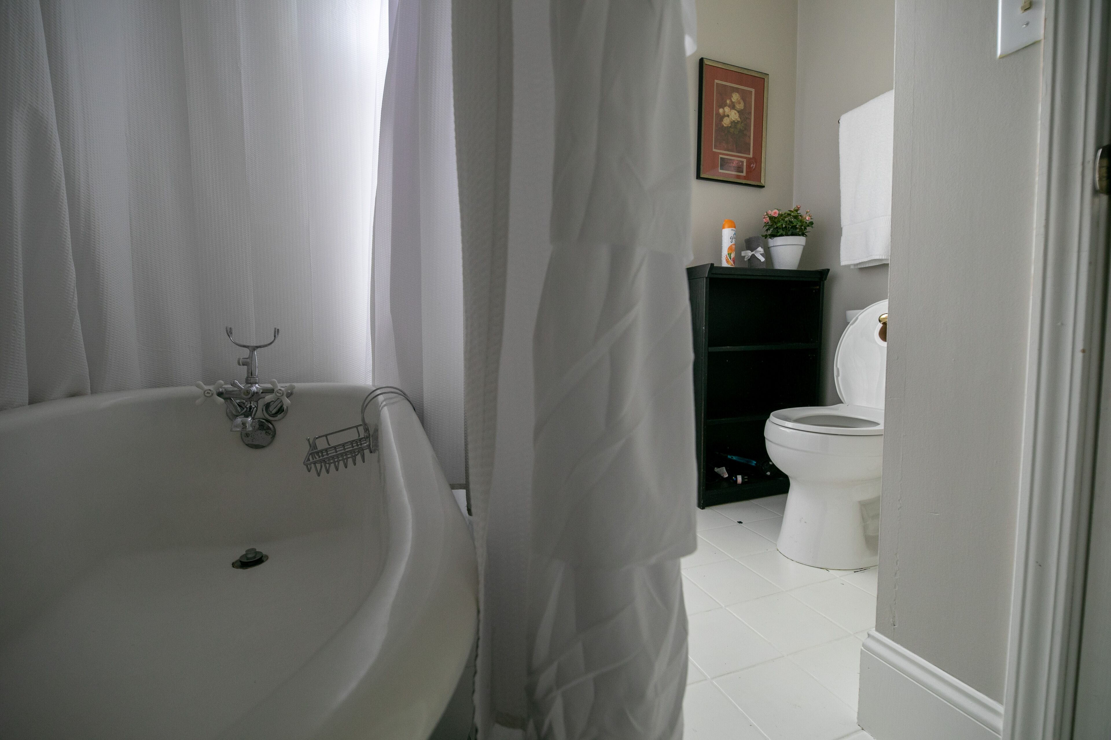 Une salle de bain avec une baignoire, des toilettes et une étagère contenant des articles de toilette.