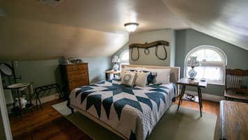 A bedroom with a bed, dresser, vanity, and a window with a view.