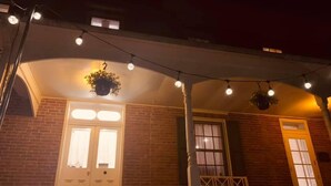 A brick building with a porch, white doors, and hanging lights. - Willard Richards Inn (Nauvoo)