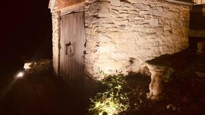 A stone building with a wooden door, illuminated by exterior lighting. - Willard Richards Inn (Nauvoo)