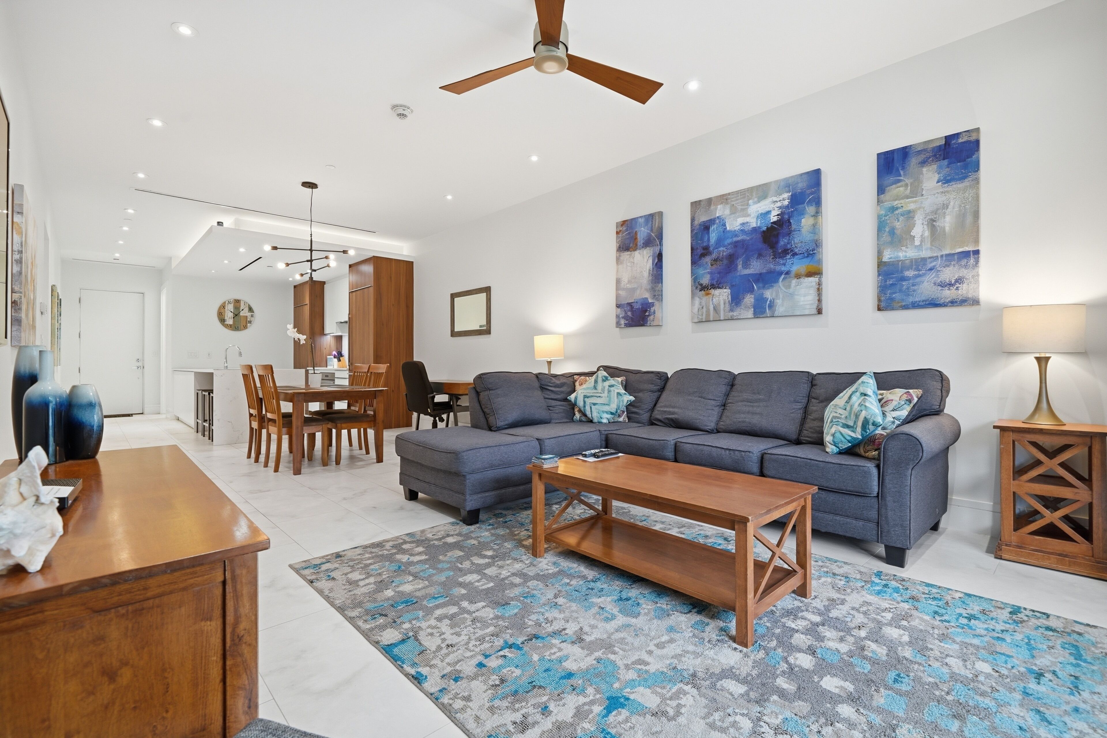A modern living room with a sofa, coffee table, and a dining area with chairs and a table.