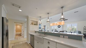 A modern kitchen with white cabinetry, a stainless steel refrigerator, a double sink, and pendant lighting. - Dot's Beach Retreat - Close to Shops, Dining & the Beach! Free Bikes/Fitness/Tennis (Rosemary Beach)