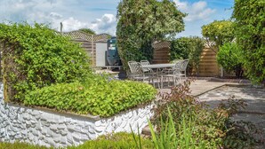 A patio area with a stone wall, a wooden fence, and a table with chairs. - 2 bedroom accommodation in Llansteffan, near Carmarthen (Llansteffan, near Carmarthen)
