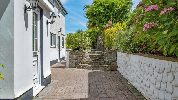 A white building with a stone wall and a paved pathway leading to a staircase. - 2 bedroom accommodation in Llansteffan, near Carmarthen (Llansteffan, near Carmarthen)