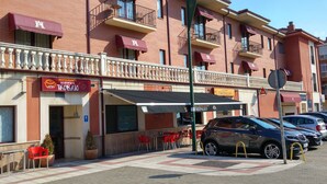 Un immeuble doté de nombreux balcons, un restaurant appelé « La Torta de Tolo » avec une terrasse, et un café nommé « Trepalio ».