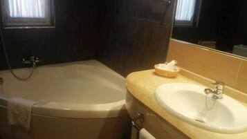 A bathroom with a bathtub, a sink, and a mirror.