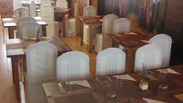 A restaurant with wooden tables and white chairs, brick walls, and a mural of barrels.
