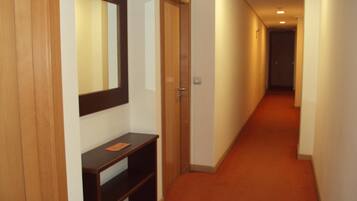 A hallway with a wooden door, a mirror, and a small wooden console table.