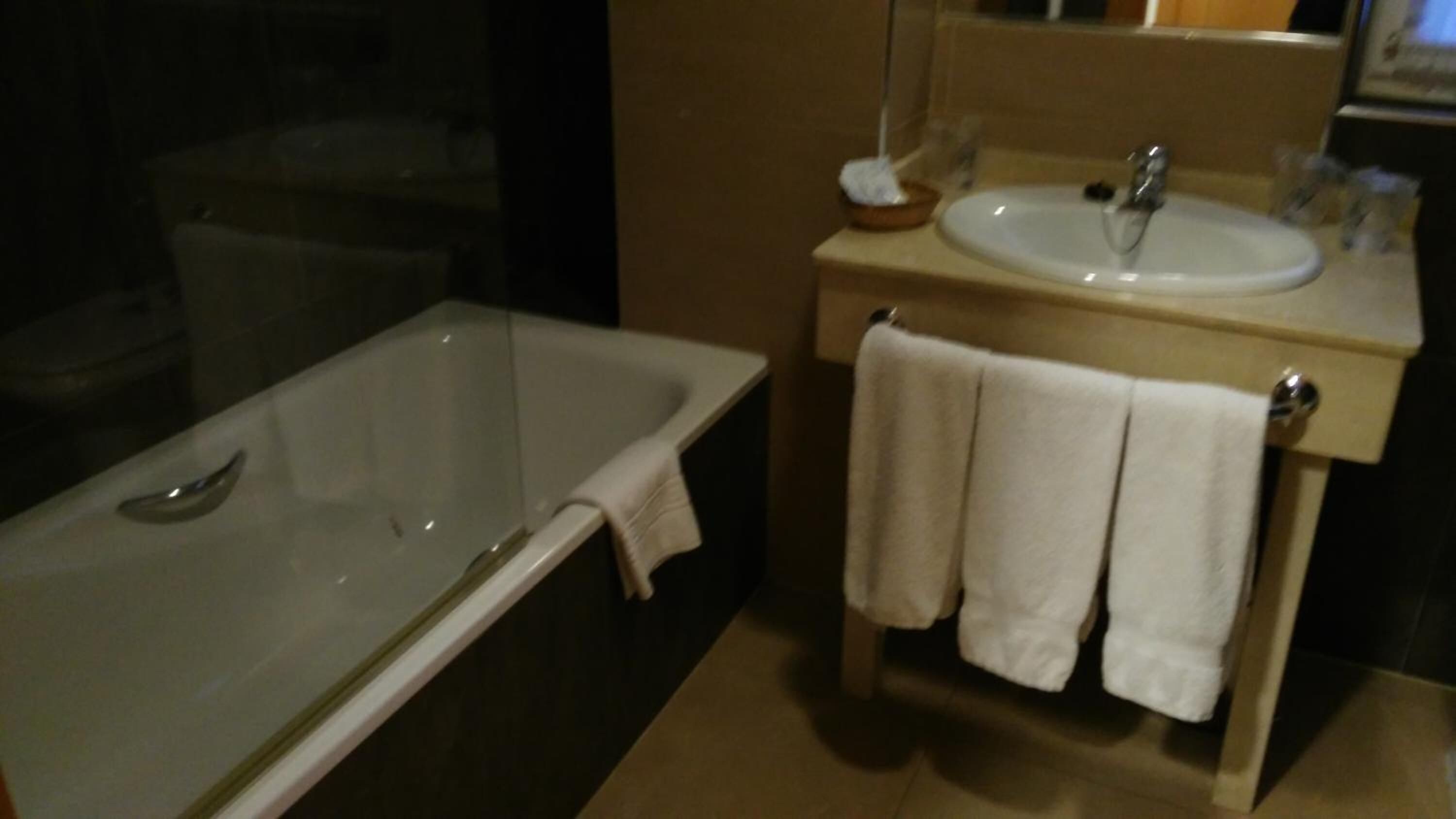 A bathroom with a bathtub, a sink, and a mirror.
