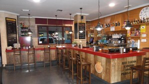 Un espace bar doté de comptoirs en bois, de nombreux tabourets et de luminaires suspendus.