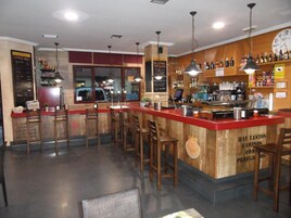 A bar area with wooden bar counters, multiple stools, and hanging pendant lights.