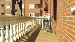 Un balcon doté d’une balustrade blanche, d’un mur en briques et d’une table avec des chaises.