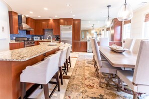 Una cocina moderna con encimeras de granito, electrodomésticos de acero inoxidable y una isla central con taburetes de bar.