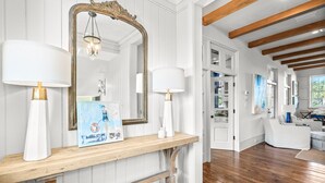 A wooden console table with two white lamps, a large mirror, and a framed picture. - Carmel Cottage - SOUTH OF 30A, FREE GYM/TENNIS, ELEVATOR, BEAUTIFUL OUTDOOR AREA (Rosemary Beach)