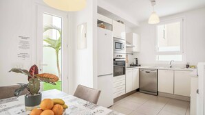 Une cuisine moderne avec des armoires blanches, un four encastré, un four à micro-ondes et un lave-vaisselle.
