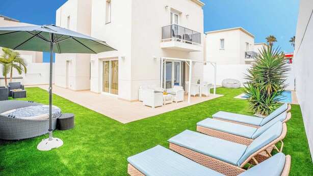 Un bâtiment moderne à deux étages, doté d’un balcon, d’un espace extérieur aménagé pour s’asseoir et d’une pelouse bien entretenue.