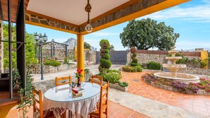 Relax in a serene outdoor space surrounded by lush greenery and a stone fountain.