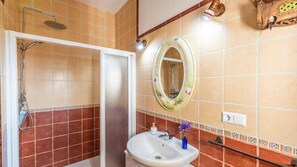 Enjoy a refreshing shower in the walk-in shower with a handheld showerhead, complemented by a sink and mirror.