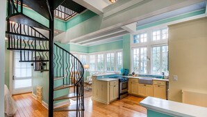 A spacious kitchen with a central island, a spiral staircase, and large windows.