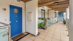 A corridor with a blue door, a white electrical box, and potted plants. - 2 bedroom accommodation in Westward Ho! (Westward Ho!)