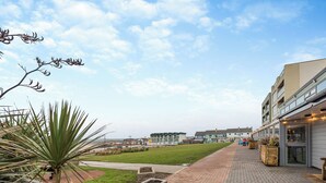 A pathway leading to a building with a modern design, a grassy area, and a palm tree. - 2 bedroom accommodation in Westward Ho! (Westward Ho!)