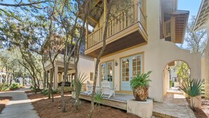 Uma casa com deck de madeira, espaço de estar ao ar livre e um grande cachepot.