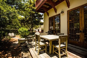 Eine Terrasse im Freien mit Holzmöbeln, darunter ein Tisch und Stühle, sowie ein Grill.