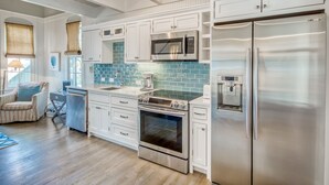 A modern kitchen with white cabinetry, stainless steel appliances, and a blue-tiled backsplash.