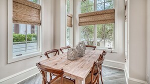 Un comedor con una mesa de madera, seis sillas y tres jarrones decorativos.