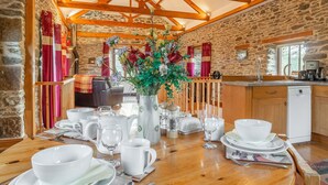 Un comedor rústico con una mesa de madera dispuesta para una comida, paredes de piedra y una chimenea de piedra.